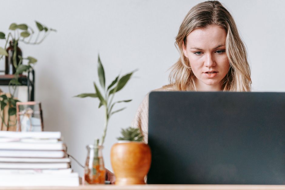 Professional woman sits calmly at her desk, focused on her laptop in a bright and modern office, embodying a centered appr...