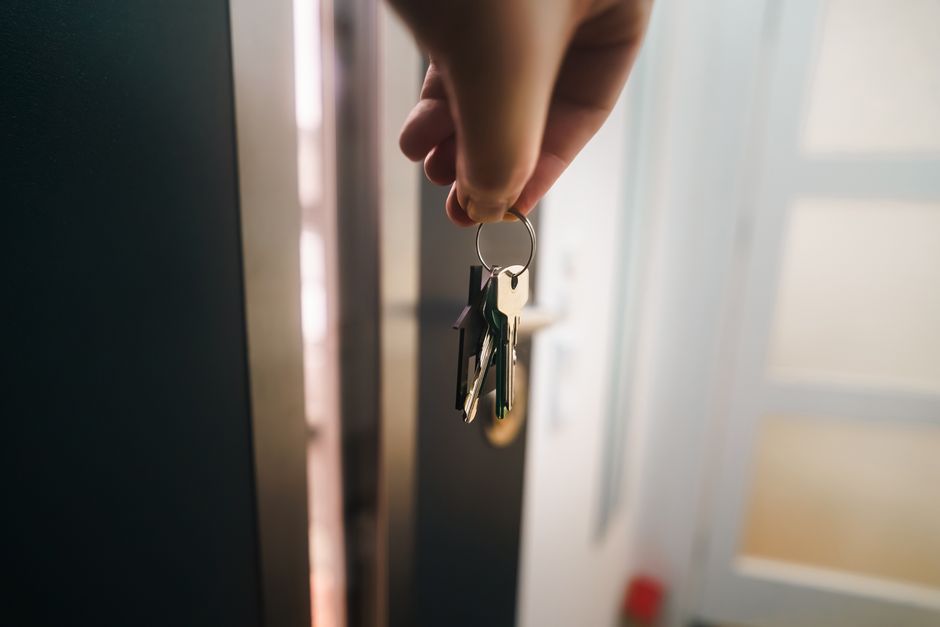 A close-up shot of a person's hand holding a set of house keys against a clean, minimalist background, symbolizing a smart and efficient real estate transaction.