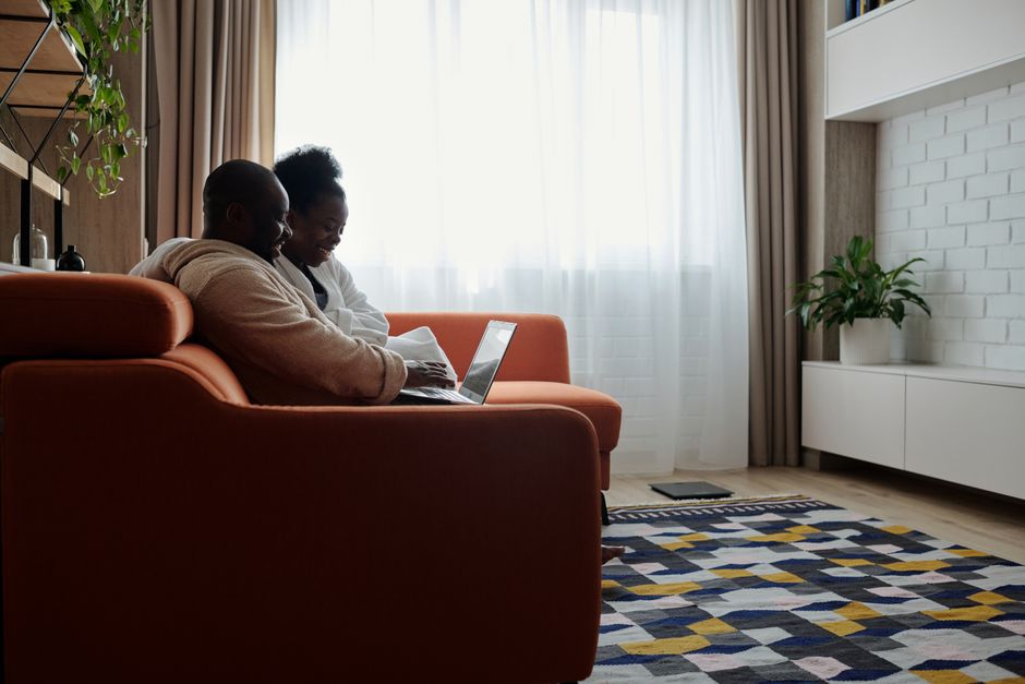 A happy couple celebrating in the living room of their bright, modern home, conveying the financial relief and joy of saving money on their home sale.